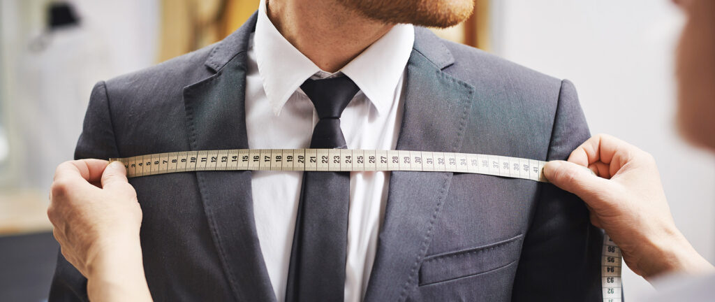 Header hosting artikel - afbeelding van man wiens maatpak wordt opgemeten