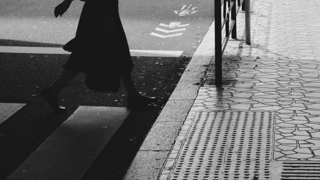 Zwart-witfoto in Tokio, voetgangerspad, silhouet van voetganger die de straat oversteekt, ribbelstrook.