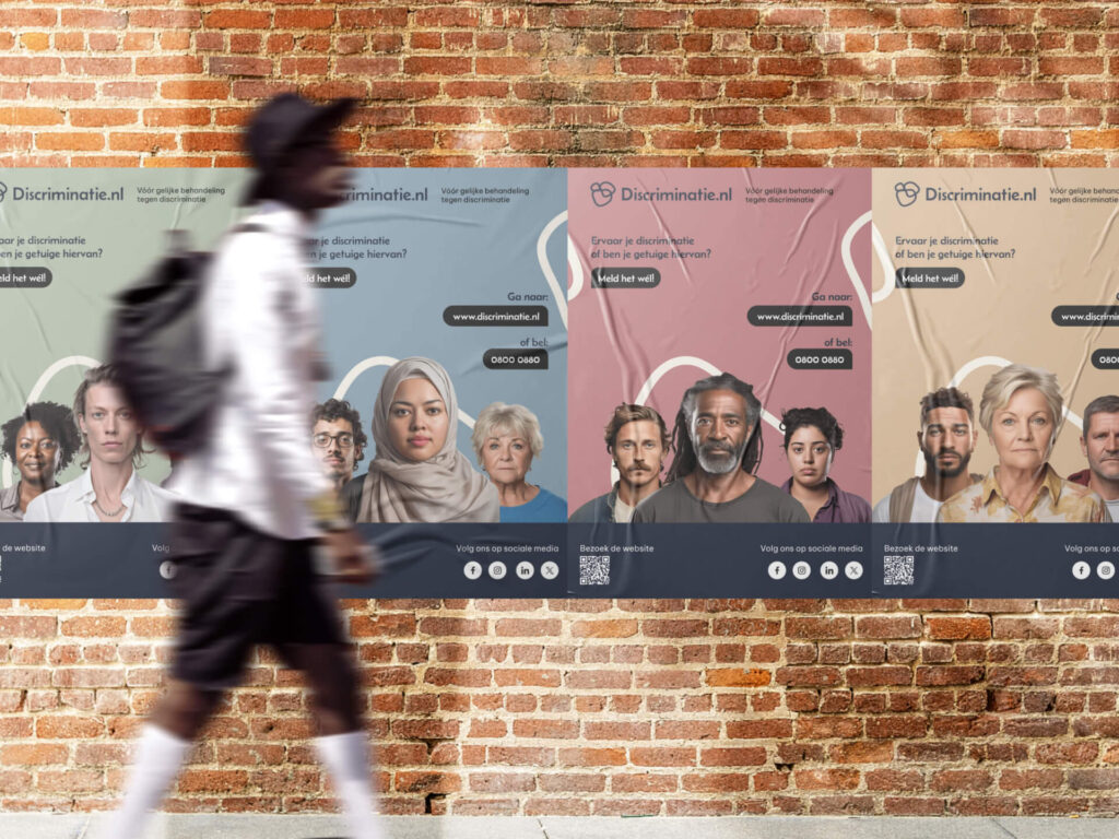 Drie grote posters van Discriminatie.nl hangen naast elkaar op een bakstenen muur, met diverse groepen mensen en de slogan "Meld het wél!". Op de voorgrond loopt een man met een rugzak, van wie alleen het silhouet en de beweging te zien zijn.