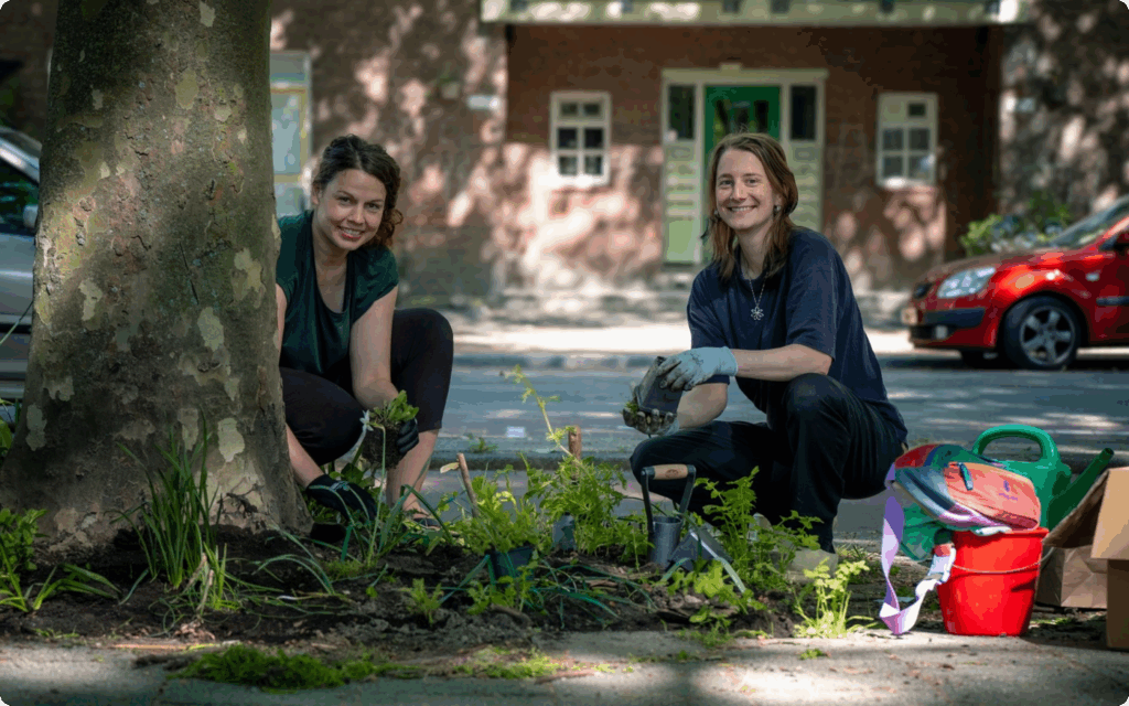 Twee vrouwen zijn in hun straat bezig met het planten van plantjes.