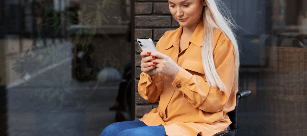 Vrouw in rolstoel met mobiele telefoon in hand.