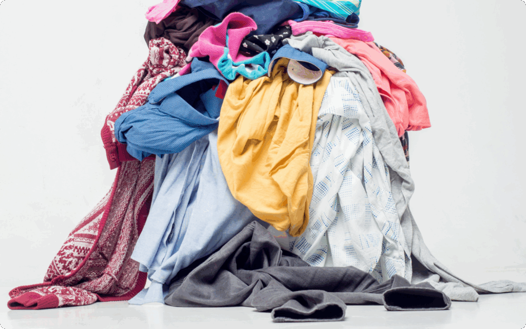 Grote, kleurrijke stapel gebruikte kleding en textiel op een witte achtergrond.