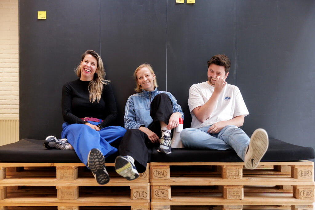 drie collega's van Level Level relaxen op een bankje op kantoor