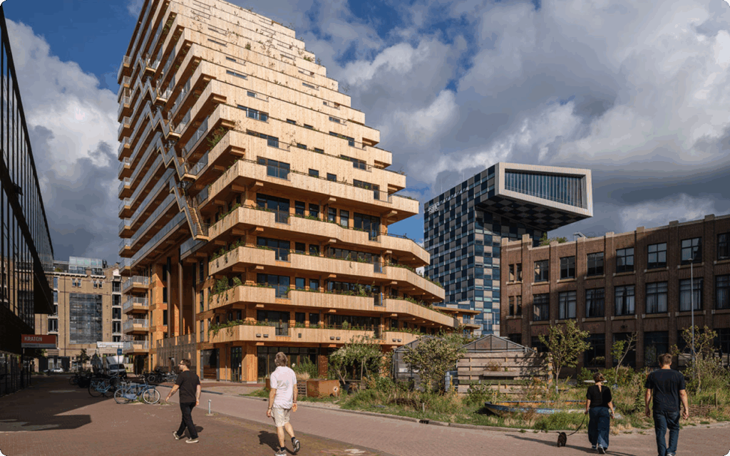Het houten woongebouw SAWA in Rotterdam met groene terrassen, met op de achtergrond het STC-gebouw onder een bewolkte lucht.