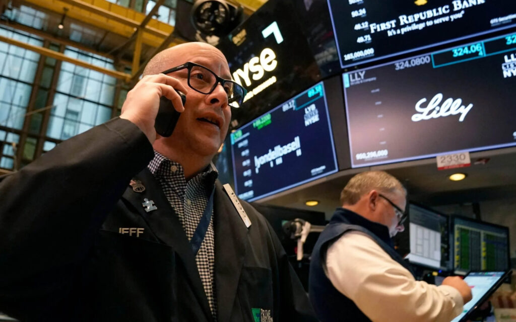 Een beurshandelaar met bril en headset voert geconcentreerd een telefoongesprek op de vloer van de New York Stock Exchange (NYSE).