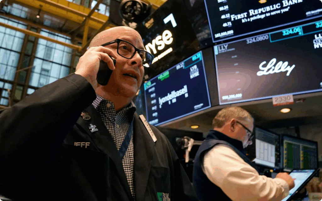Een beurshandelaar met bril en headset voert geconcentreerd een telefoongesprek op de vloer van de New York Stock Exchange (NYSE).