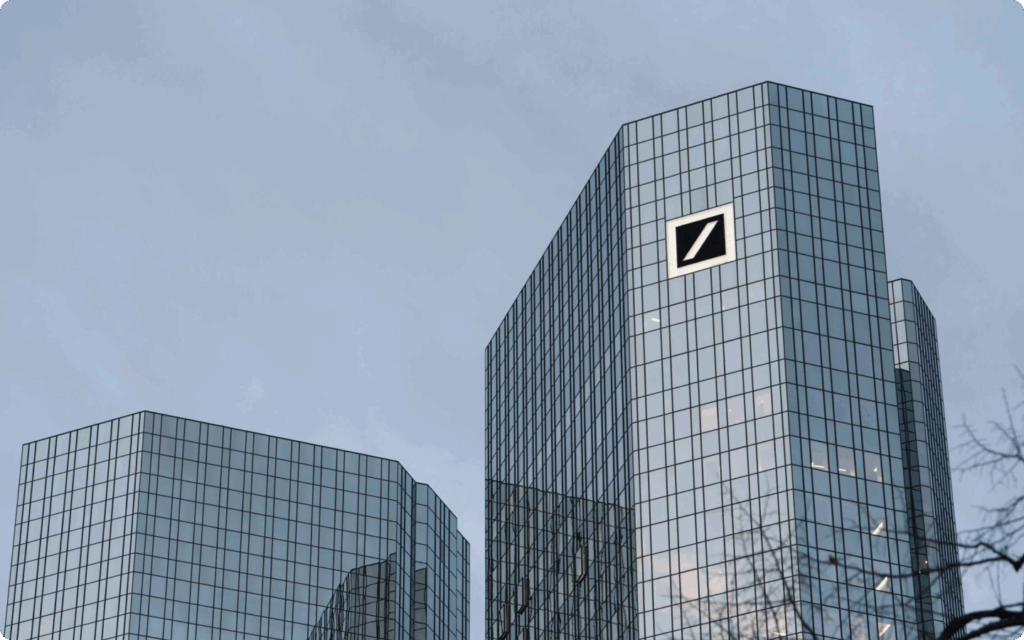 De moderne glazen wolkenkrabbers van het hoofdkantoor van de Deutsche Bank in Frankfurt tegen een grijze lucht.