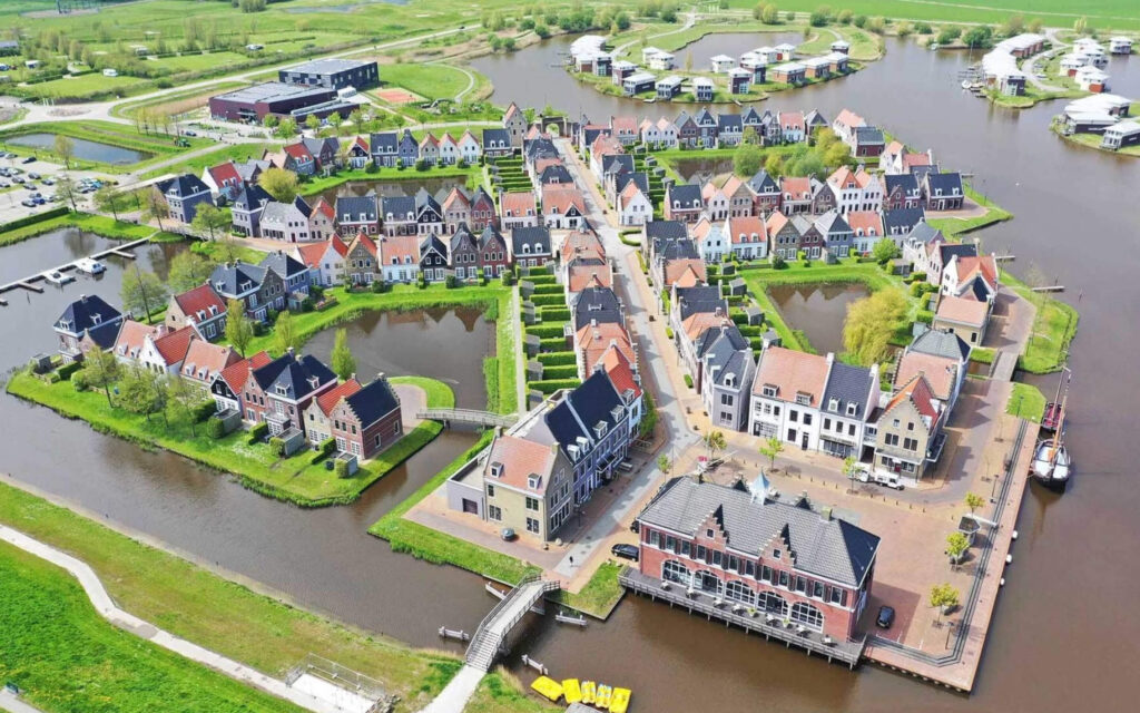 Een luchtfoto van een vakantiepark met rijen wit-grijze huizen die zijn gebouwd op landtongen omringd door waterwegen.